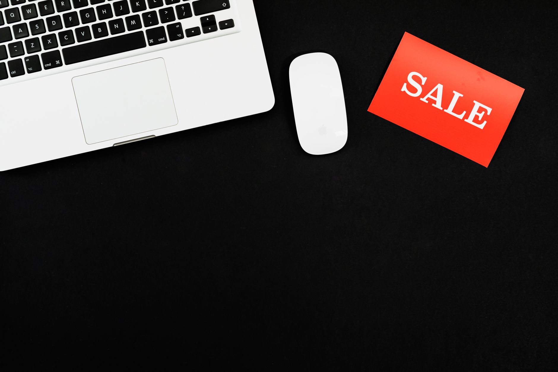 Minimalist flat lay of a laptop, mouse, and a red sale sign on black background. — How to make shopping lingerie via internet