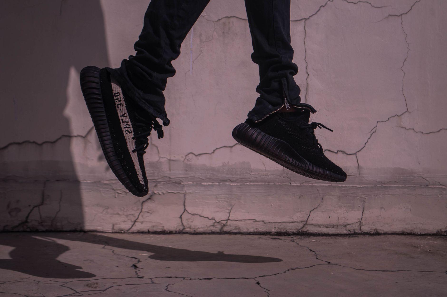 A stylish and dynamic urban photo capturing black sneakers in mid-jump against a cracked concrete wall. — Short Straight Hair